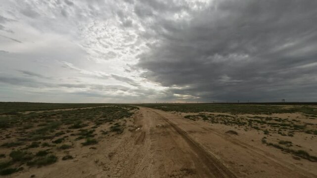 Off-road vehicle navigating dirt path through expansive desert landscape