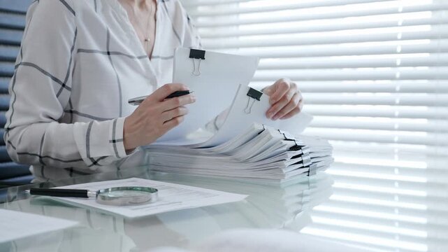 Financial auditor reviewing company documents, checking tax compliance reporting, conducting a detailed investigation, and thoroughly analyzing business paperwork for legal adherence