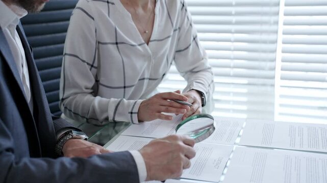 Business professional meticulously examining a legal document or contract with a magnifying glass. Emphasizing key clauses and fine print. While a colleague or client waits to review the agreement