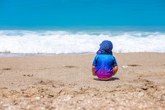 girl palying on the beach wearing sun protective clothes