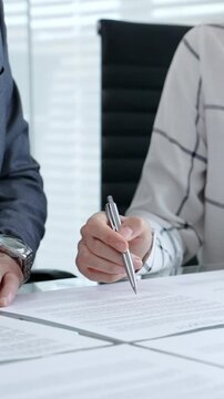 Business people engaging in a contract review, signing legal documents, finalizing a deal, discussing conditions, and making an agreement in an office setting