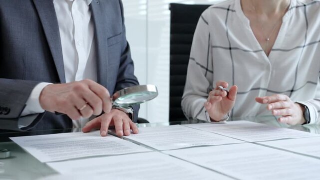 Business professionals reviewing legal contracts and important documents with a magnifying glass, performing careful examination and due diligence for risk assessment