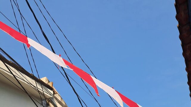 Red and white pennant flags hanging in residential area for Indonesia Independence Day. Blue sky, 17 August celebration, national holiday, patriotic.