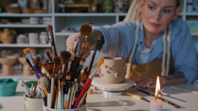 Potter selects brush for decorating handmade ceramic mug