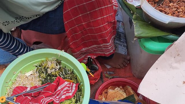 Street food vendor preparing Blitar pecel rice with peanut sauce, vegetables, serundeng and fried egg. Traditional Indonesian food, wrapped in paper.