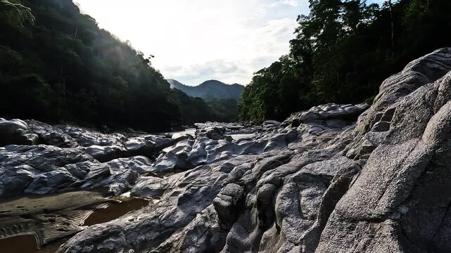 Rocky Tropical Riverbed in Ecuador with Smooth Grey Boulders, Forested Mountains, Shallow Stream and Remote Jungle Valley Landscape