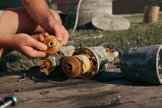 Hands holding worn rubber impeller during submersible water pump repair