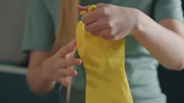 Homeowner removing yellow gloves after cleaning, folding gloves on lap, resting hands on knees, soft relief expression, quiet domestic scene, final tidy ritual, intimate closeup, calm evening mood