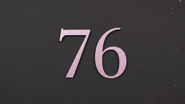 Pink Glitter Blows Away and Reveals the Number 76 on Solid Background