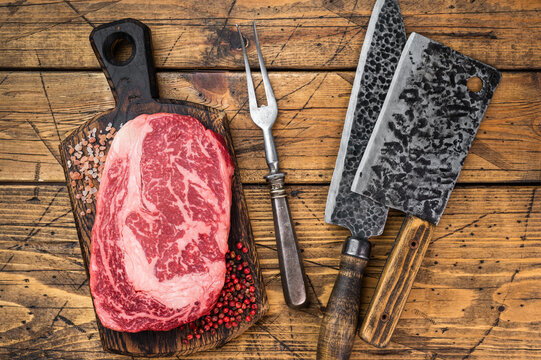 Premium raw ribeye beef steak delmonico entrecote style. Thick marbled rib cut on wooden background.