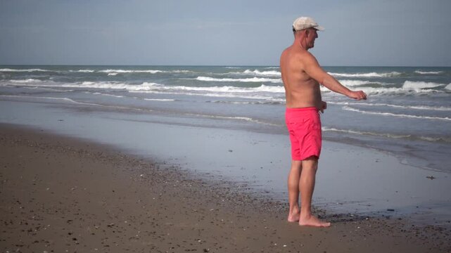 Hirtshals, Denmark A man does morning callisthenics and exercises on a sandy beach on the North Sea in summer. 