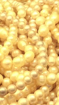 Macro view of creamy golden pearl bead strands overlapping and subtly shifting, creating a luxurious jewelry texture with soft luster and elegant decorative detail