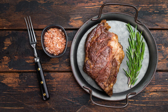 Seared beef chuck eye steak in metal pan with rosemary and salt. Tender cooked beef meat top view.