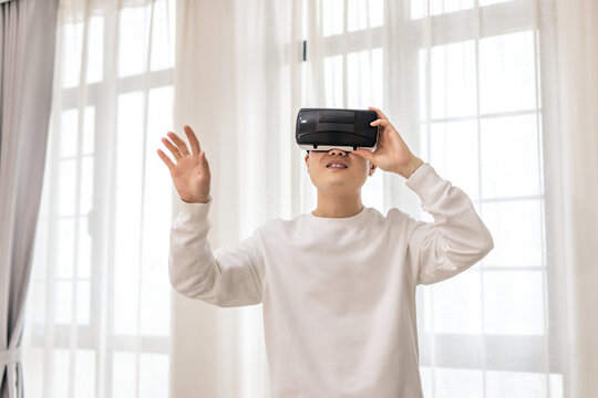 An adult man wearing a VR headset, interacting with virtual content in a bright indoor room.