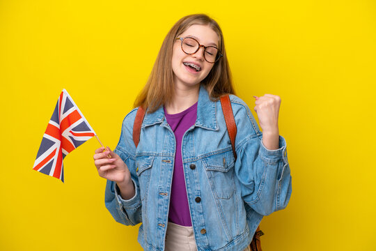 Teenager Russian girl holding an United Kingdom flag isolated on yellow background celebrating a victory