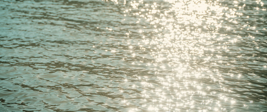 Abstract water surface background with sun glare and light reflections.