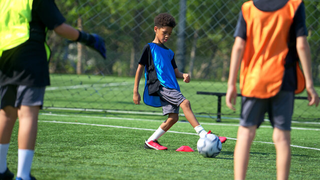 International school student practicing soccer dribbling on the field,