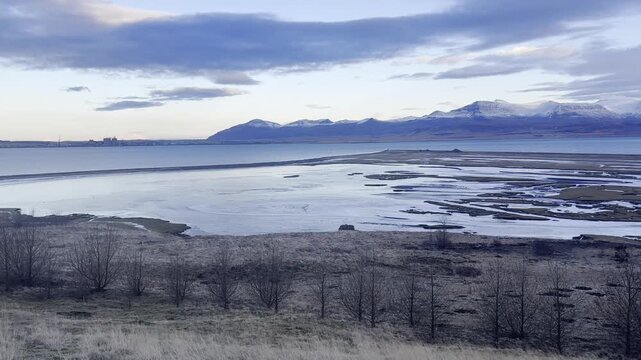 Handheld pan right showcasing Hvalfjordur fjord and snow capped mountains along Route 47 Iceland
