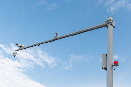 A surveillance pole with multiple monitoring cameras and equipment, set against a clear blue sky.