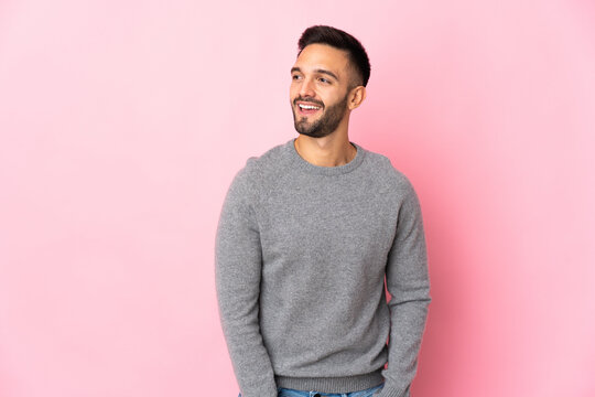 Young caucasian man isolated on pink background looking to the side and smiling