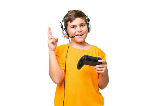 Little caucasian kid playing with a video game controller over isolated chroma key background smiling and showing victory sign