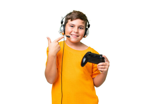 Little caucasian kid playing with a video game controller over isolated chroma key background giving a thumbs up gesture