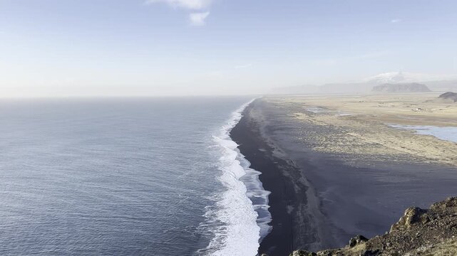 Steady locked off shot of ocean waves crashing onto volcanic black sand beach in winter Iceland