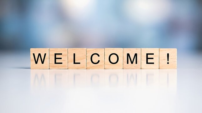 Wooden blocks spelling the word welcome arranged on a reflective surface against a soft blue blurred background