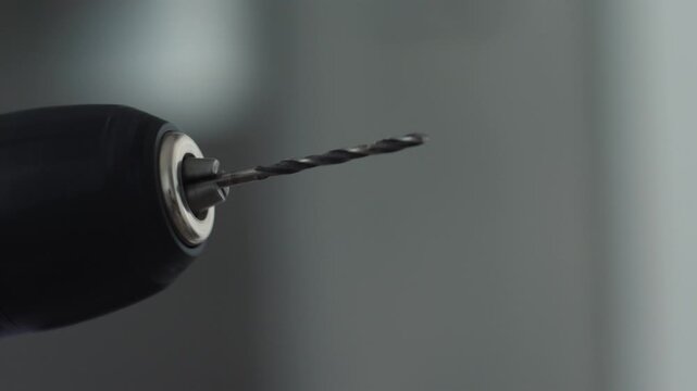 Close up of a thin drill bit clamped in the chuck of an electric power drill. Professional tool ready for work during home renovation and furniture assembly
