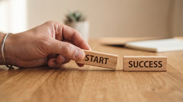 Hand placing wooden block reading "START" next to block reading "SUCCESS," symbolizing the journey