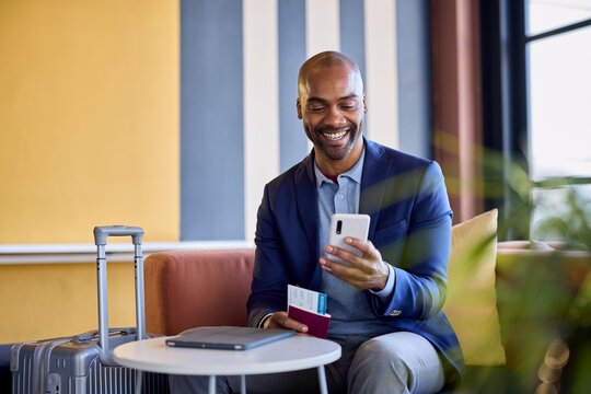 Smiling african businessman at airport using phone