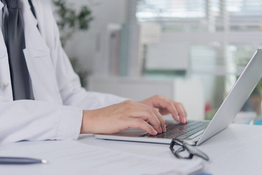 Doctor hands typing on laptop keyboard for online telemedicine consultation