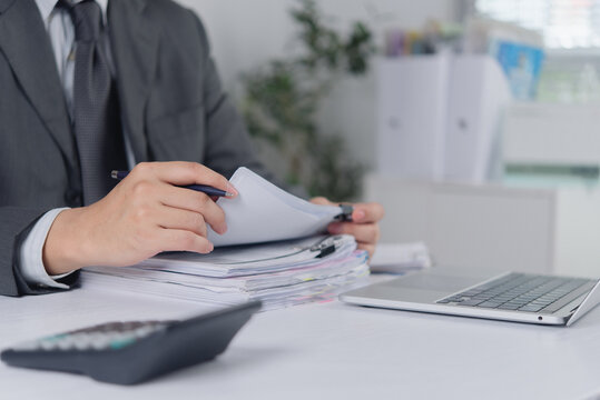 Businessman hands reviewing thick stack of paperwork and documents for financial audit