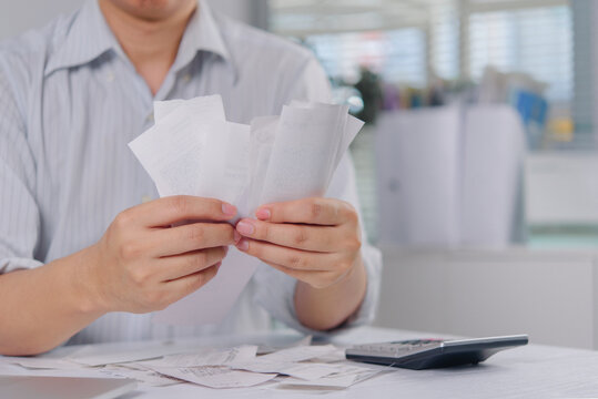 Man holding many paper receipts and bills for accounting and tax calculation at desk