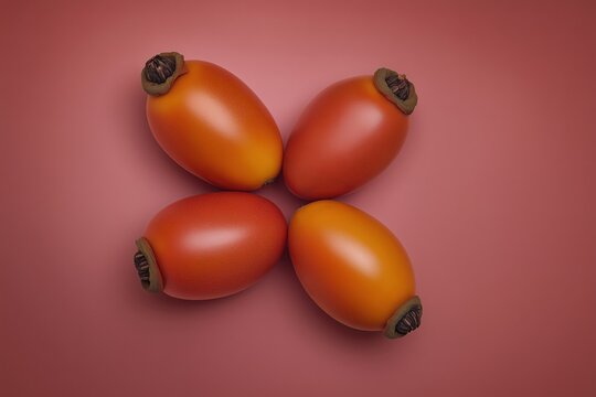 Four ripe persimmons arranged on a pink background with soft shadows