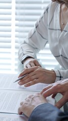 Obraz na płótnie Canvas Business woman explaining contract details to a client, pointing to important clauses with a pen during a professional meeting or negotiation, finalizing agreement