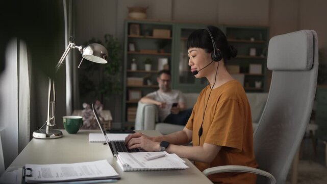 Asian call center agent working remotely from her living room