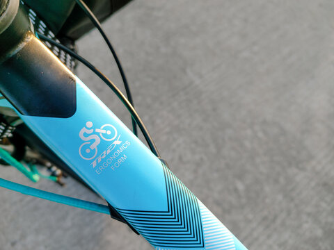 Close-up of cyan blue bicycle frame showing TREX Ergonomics Form branding logo and cables for modern bike detail