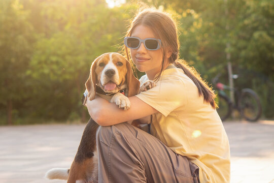 Young Woman Holding Beagle Face to Face Outdoors