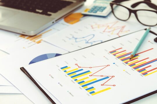 Financial report with bar charts laptop and eyeglasses on office desk eyeglasses business analysis