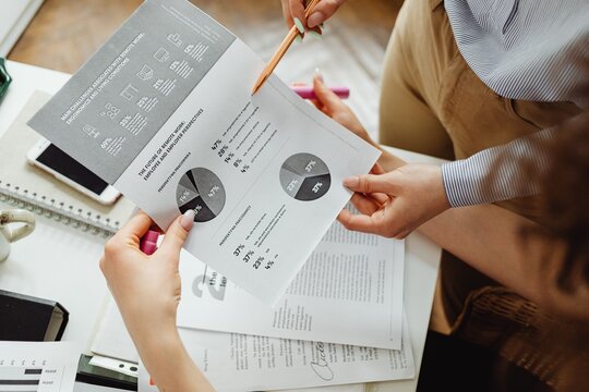 Colleagues reviewing financial documents and market research graphics in office with business, documents