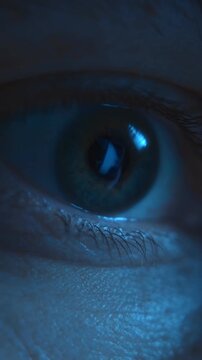 Close-up of an eye staring at a computer or smartphone screen after abruptly waking up in the dark of night. Insomnia, sleep disorder, eyestrain. Vertical video