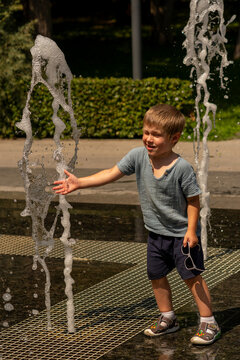 Young Boy Reaching Toward Outdoor Fountain Water Jet