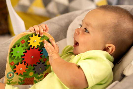 Smiling Baby Boy Holds Colorful Wooden Gear Puzzle