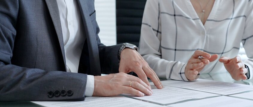 Business professionals reviewing legal contracts and important documents with a magnifying glass, performing careful examination and due diligence for risk assessment