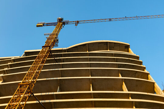 Construction crane at an abandoned construction site, bottom view, yellow and brown tones