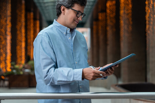 Focused businessman holding a clipboard and pen in a modern inte