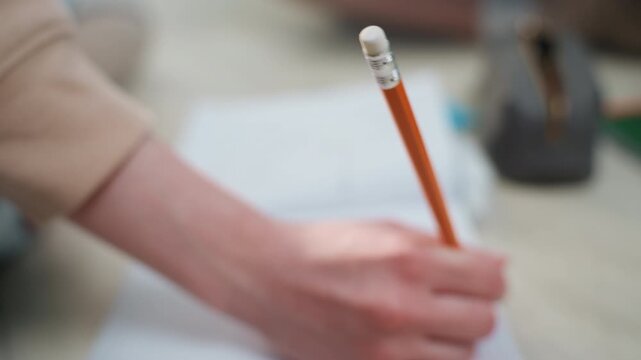 White woman practicing pencil handwriting closeup tight studiostyle closeup of sharpened pencil and right hand over grid notebook, visible eraser tip, gentle bokeh background, measured pressure
