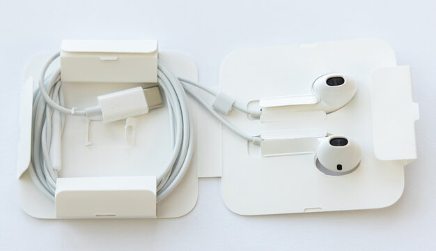 New white wired earphones in open cardboard packaging on white