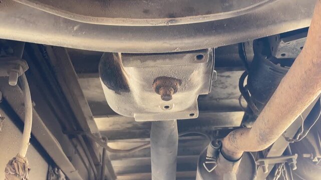 commercial truck axle housing leaf spring assembly during carwash process showing undercarriage chassis of heavy duty vehicle for cleaning maintenance inspection outdoor station.